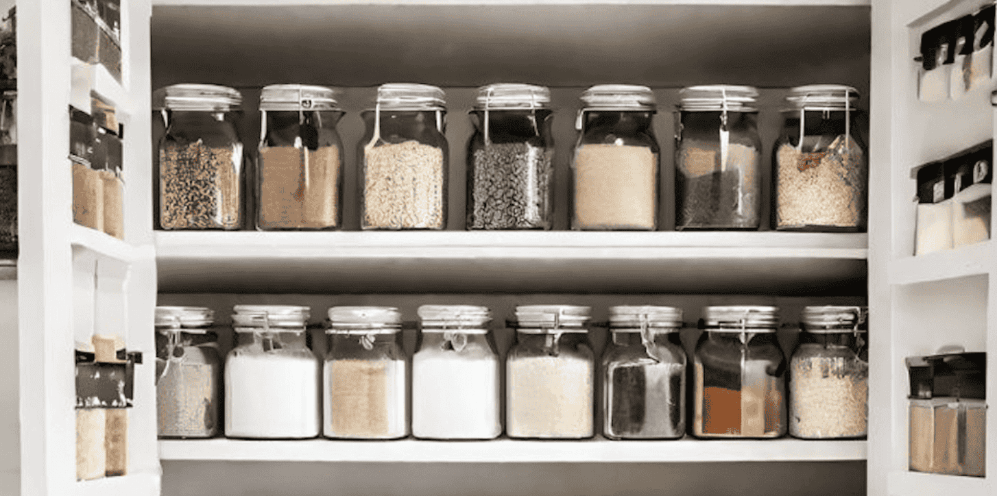 Affordable vegan pantry essentials including plant-based butter, oat milk, canned tomatoes, pasta, tofu, and spices arranged for everyday plant-based cooking.